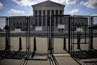 A photo shows the exterior of the U.S. Supreme Court blocked by fencing. Signs on the fences read, "Area closed."