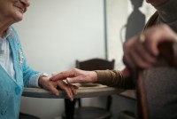 Midsection of older man touching older woman's hand in caf茅.