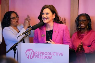 A photo of Michigan Governor Gretchen Whitmer speaking at a bill signing event.