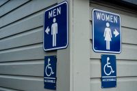 A photo of signage on a paneled building directing people to separate gendered bathrooms.